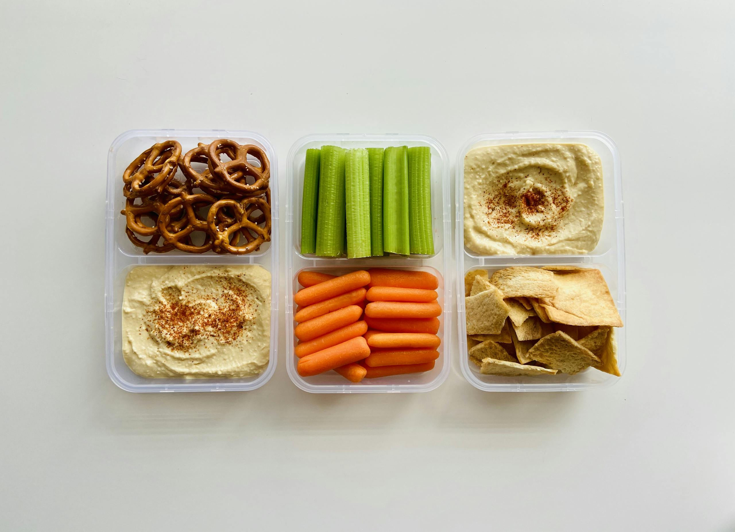 A fresh and healthy snack platter with hummus, vegetables, and pretzels.