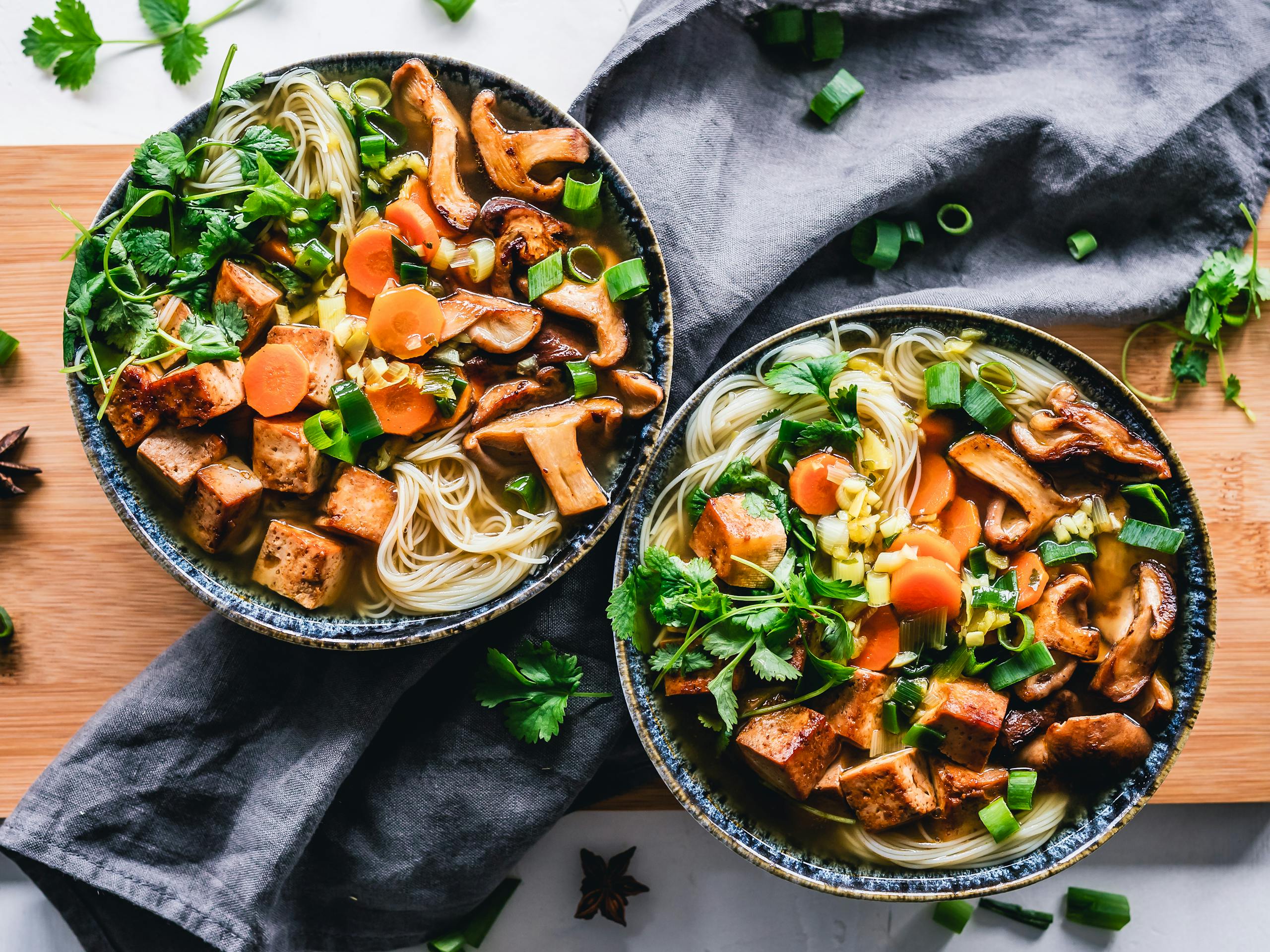 A vibrant noodle bowl with tofu, mushrooms, and fresh vegetables.