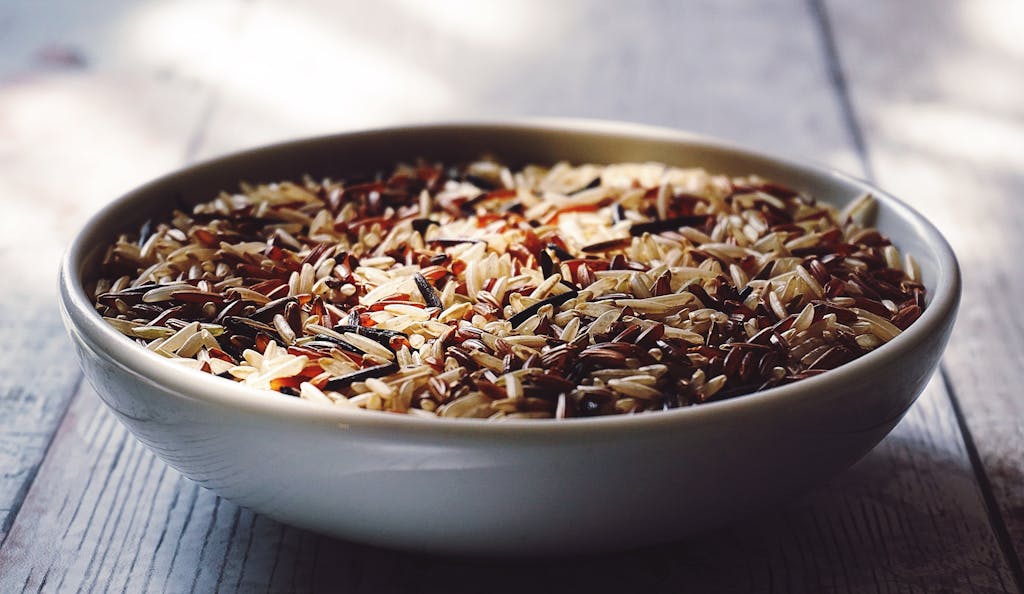 Close-up view of a bowl filled with mixed wild and brown rice grains.