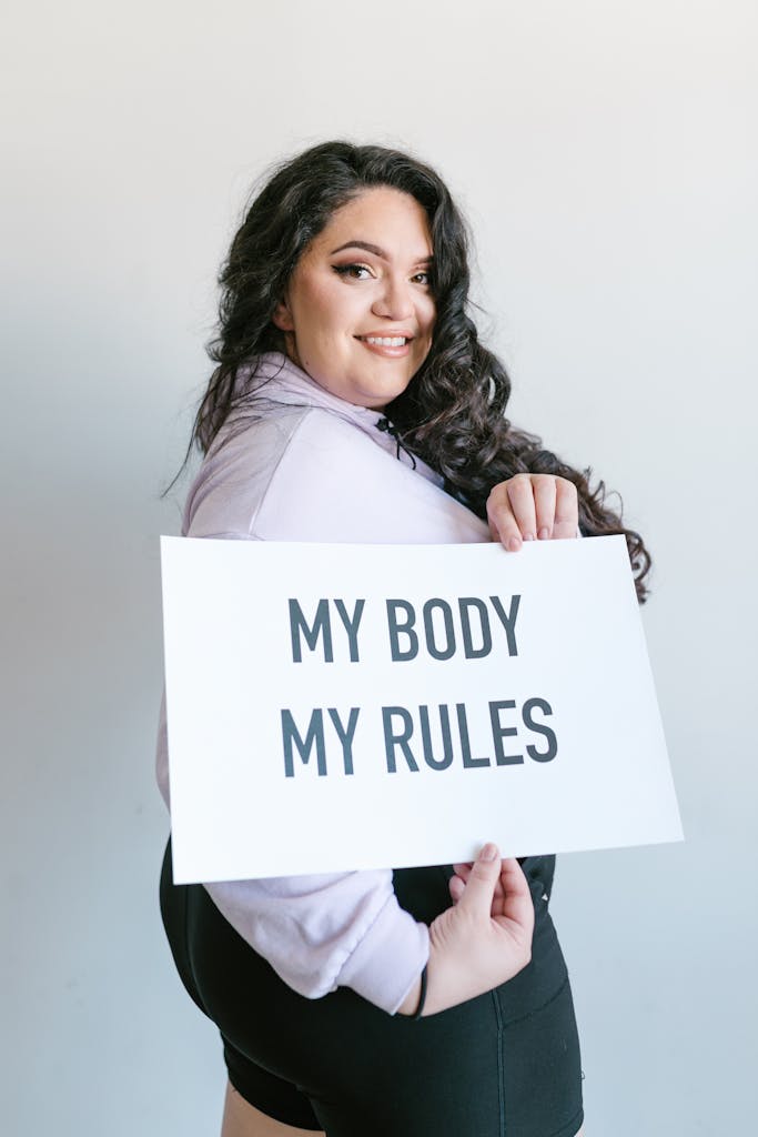 Confident woman holds sign promoting body autonomy. Sign says my body my rules