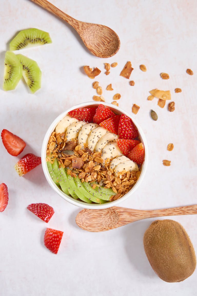 Delicious granola bowl with banana, kiwi, strawberries, and seeds.