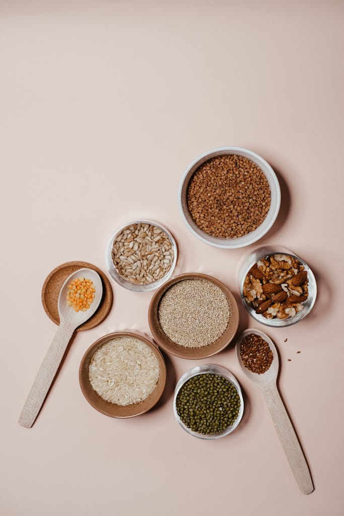 Assortment of whole grains, lentils and nuts in bowls and wooden spoons on neutral background. These foods are high in soluble fiber and can lower cholesterol levels. 